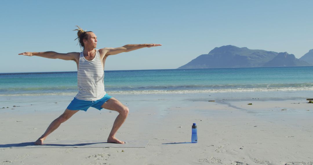 Man Practicing Yoga in Warrior Pose on Beach with Mountains in Background - Free Images, Stock Photos and Pictures on Pikwizard.com