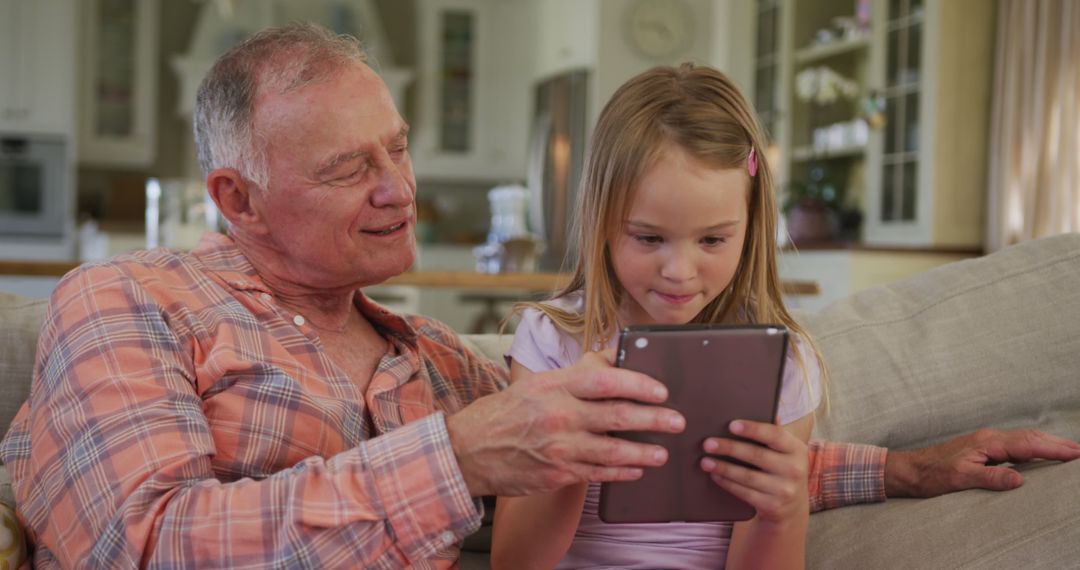 Grandfather and Granddaughter Using Digital Tablet in Living Room - Free Images, Stock Photos and Pictures on Pikwizard.com