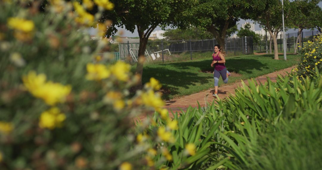 Woman Jogging Through Sunny Park with Vibrant Flowers - Free Images, Stock Photos and Pictures on Pikwizard.com