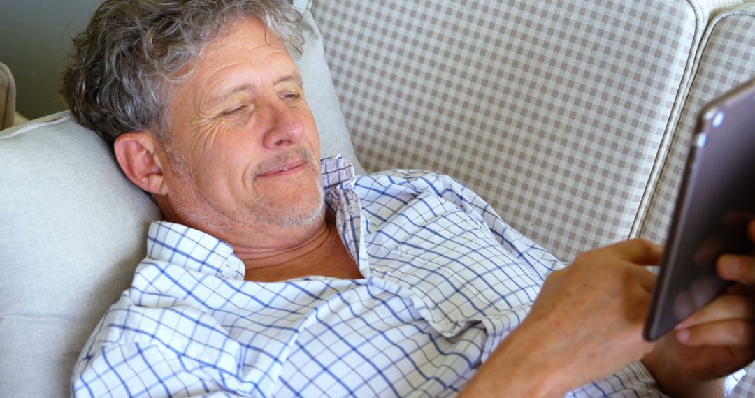 Senior Man Relaxing on Sofa Using Tablet - Free Images, Stock Photos and Pictures on Pikwizard.com