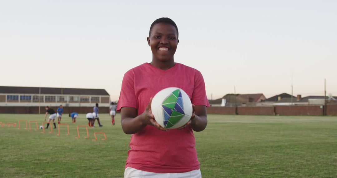 Female Coach Smiling on Soccer Field Holding Ball - Free Images, Stock Photos and Pictures on Pikwizard.com