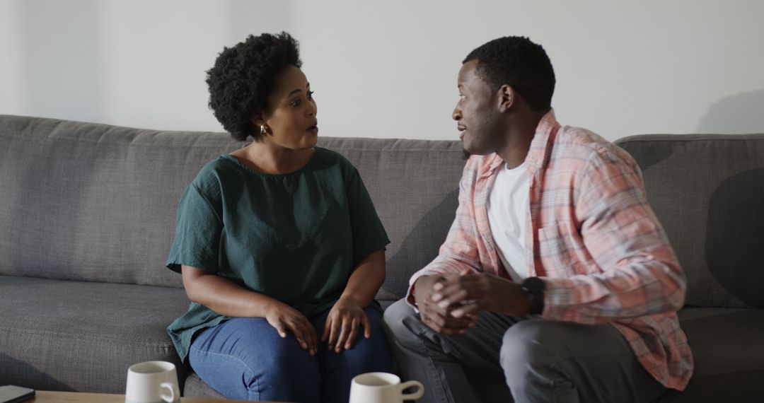 Man Proposing with Ring to Excited Woman on Sofa in Joyful Moment