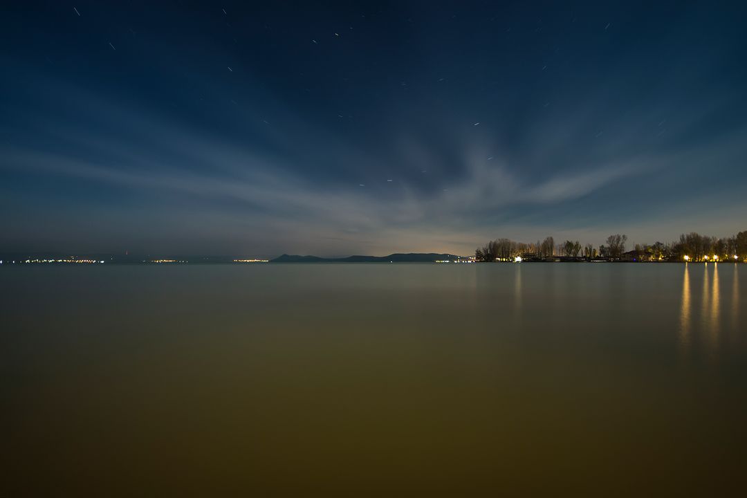 Tranquil Night Sky over Calm Lake with Distant Lights - Free Images, Stock Photos and Pictures on Pikwizard.com