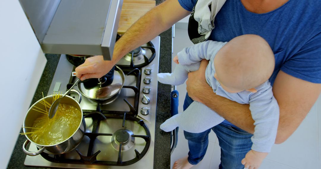 Father Cooking Pasta While Holding Baby at Home - Free Images, Stock Photos and Pictures on Pikwizard.com