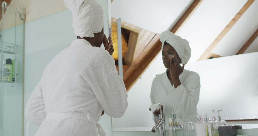 Woman Wearing Bathrobe and Towel Applying Skincare Cream in Front of Mirror - Free Images, Stock Photos and Pictures on Pikwizard.com