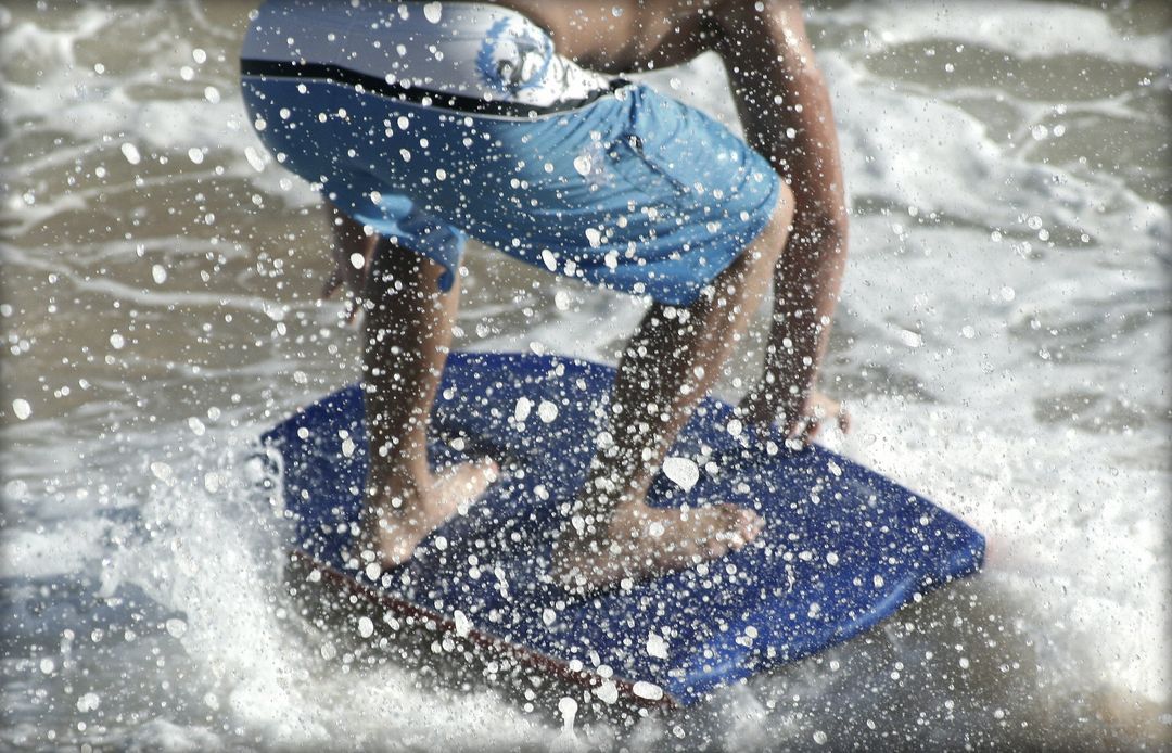 Person Skimboarding in Ocean Waves with Water Splash