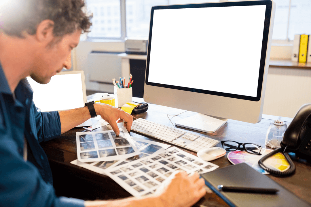 Serious Man Reviewing Photos at Desk with Blank Transparent Display