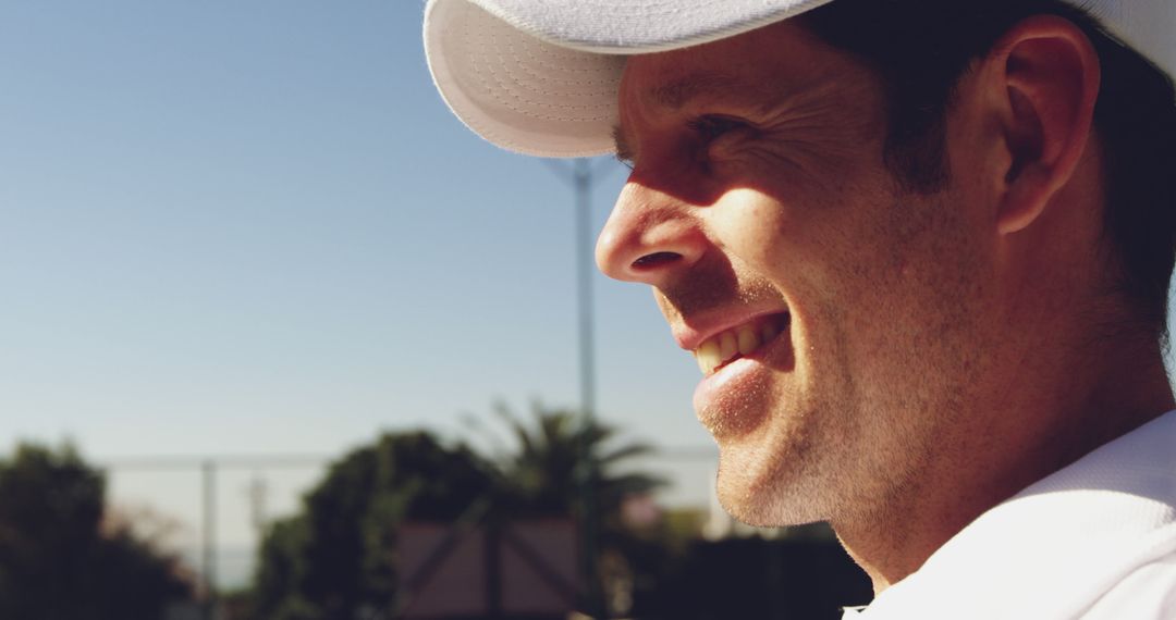 Smiling Man in Cap Enjoying Sunny Day Outdoors, Expression of Happiness