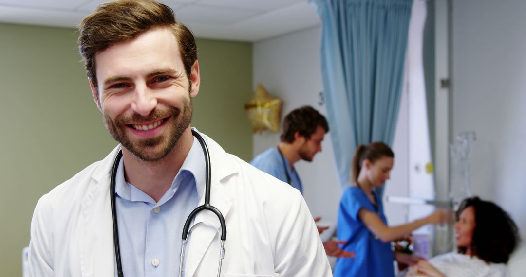 Smiling Male Doctor with Stethoscope in Busy Hospital Room - Free Images, Stock Photos and Pictures on Pikwizard.com