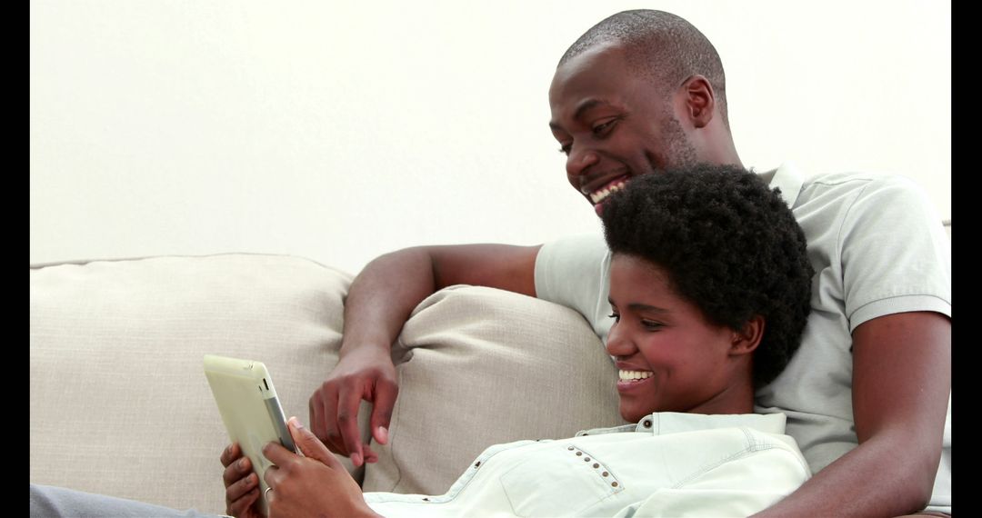Happy Couple Enjoying Tablet on Cozy Couch