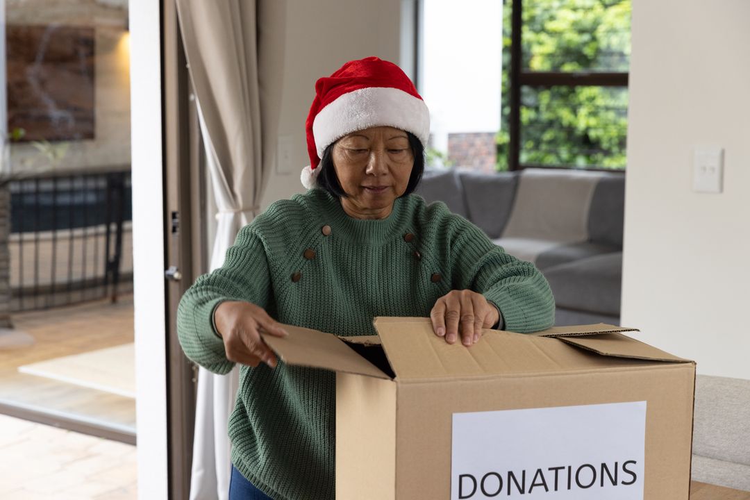 Woman in Santa Hat Preparing Donation Box at Home