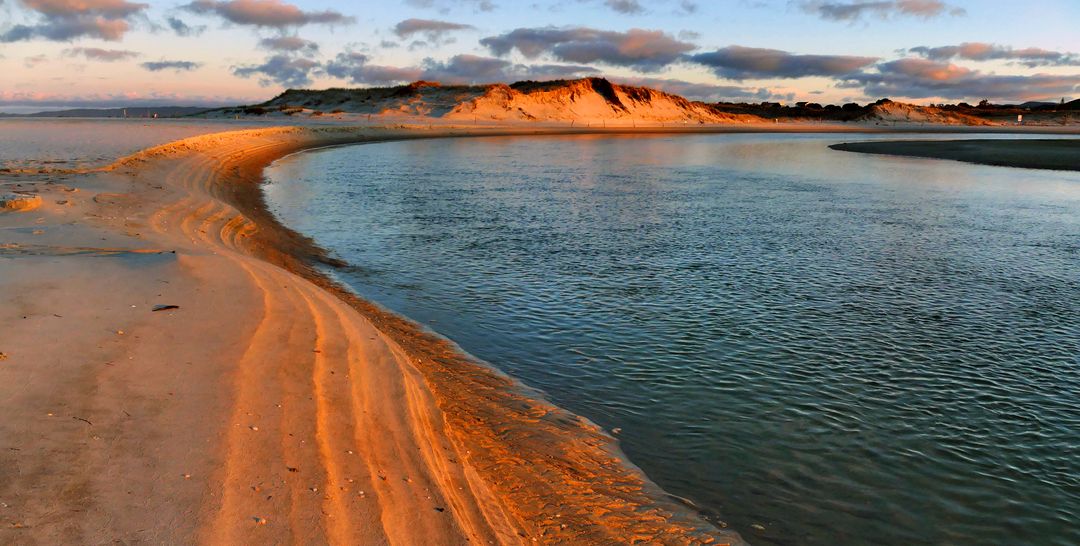 Golden Curved Sandbar Leading to Calm Tidal Lagoon with Dune Reflections at Sunset