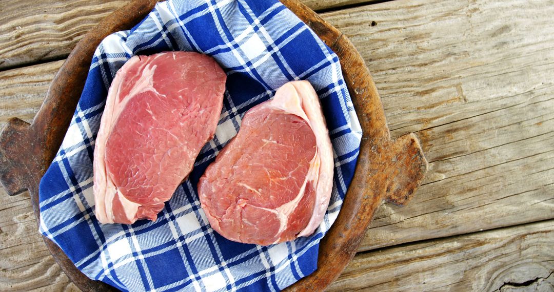 Fresh Raw Steaks on Blue Plaid Cloth on Rustic Wooden Table - Free Images, Stock Photos and Pictures on Pikwizard.com