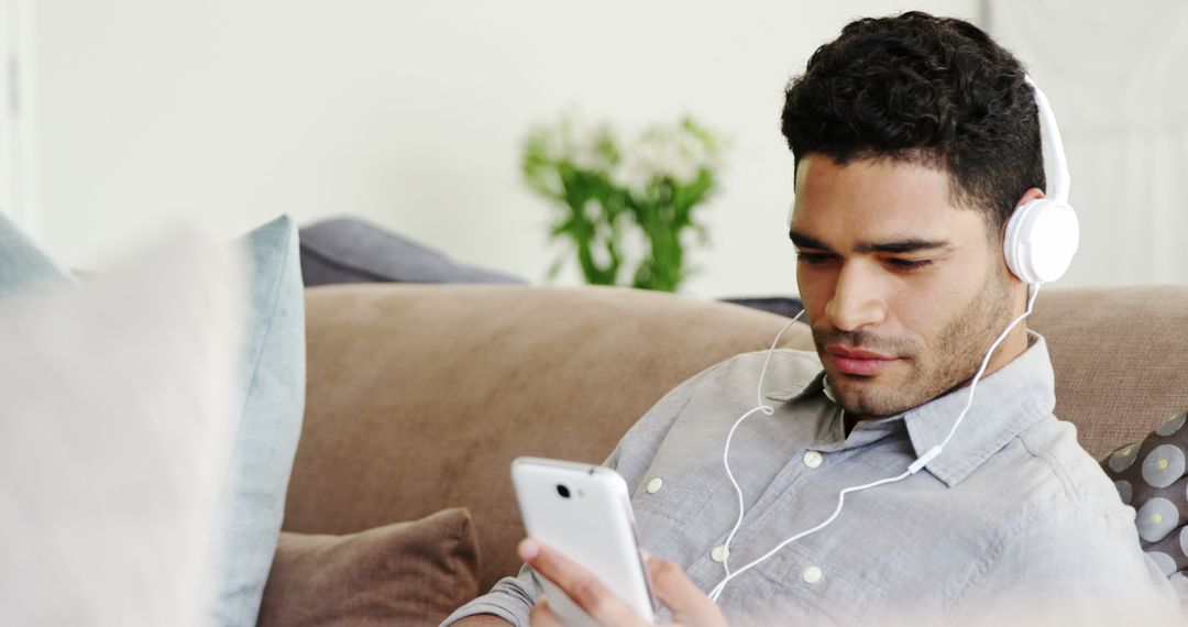 Young Man Relaxing on Couch Listening to Music with Headphones - Free Images, Stock Photos and Pictures on Pikwizard.com