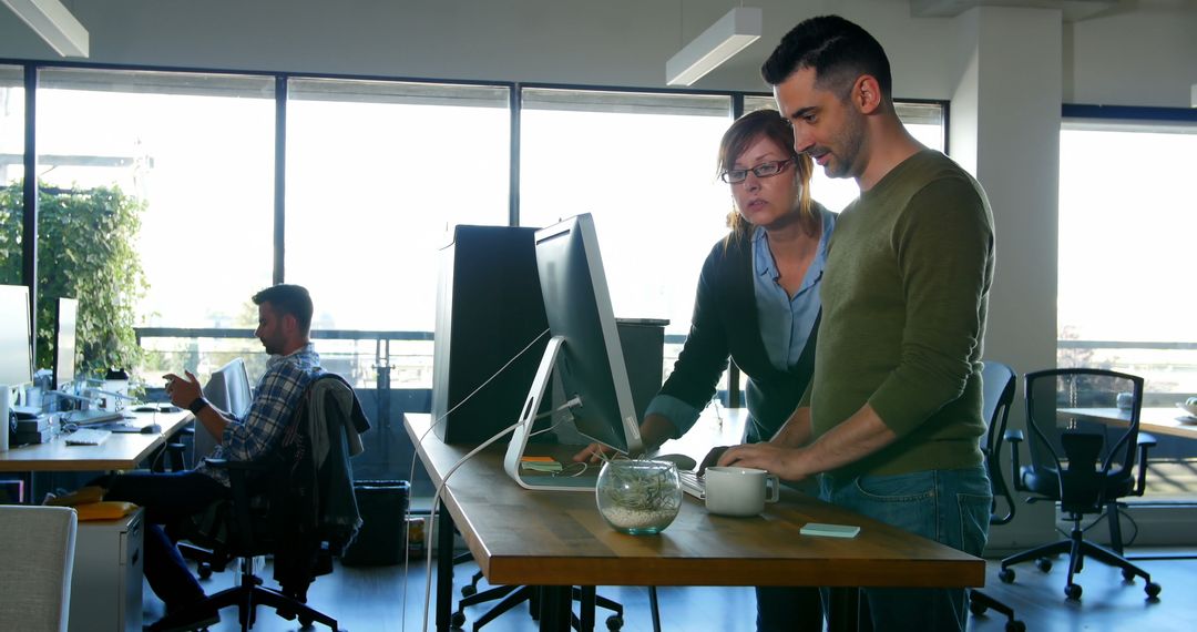 Coworkers Collaborating at Standing Desk in Modern Office - Free Images, Stock Photos and Pictures on Pikwizard.com