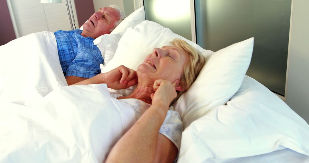 Elderly Woman Covering Ears While Man Snores in Bed - Free Images, Stock Photos and Pictures on Pikwizard.com