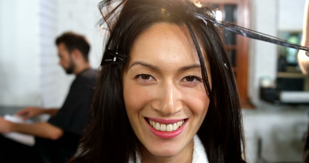 A smiling Asian woman is getting her hair styled at a salon, with copy space - Free Images, Stock Photos and Pictures on Pikwizard.com