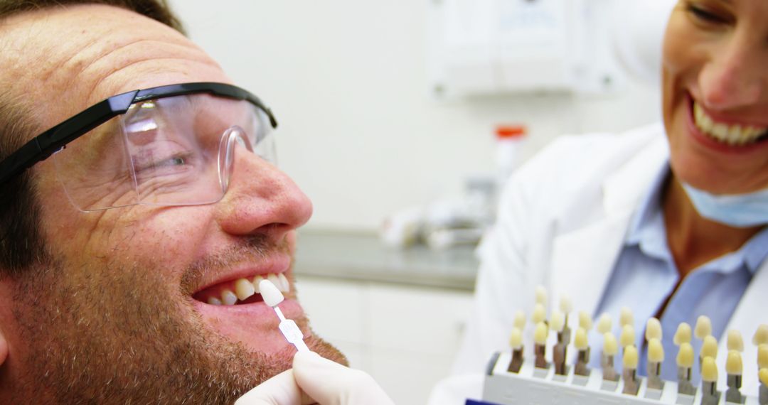 Smiling Man Receiving Dental Veneer Color Matching at Dentist Office - Free Images, Stock Photos and Pictures on Pikwizard.com