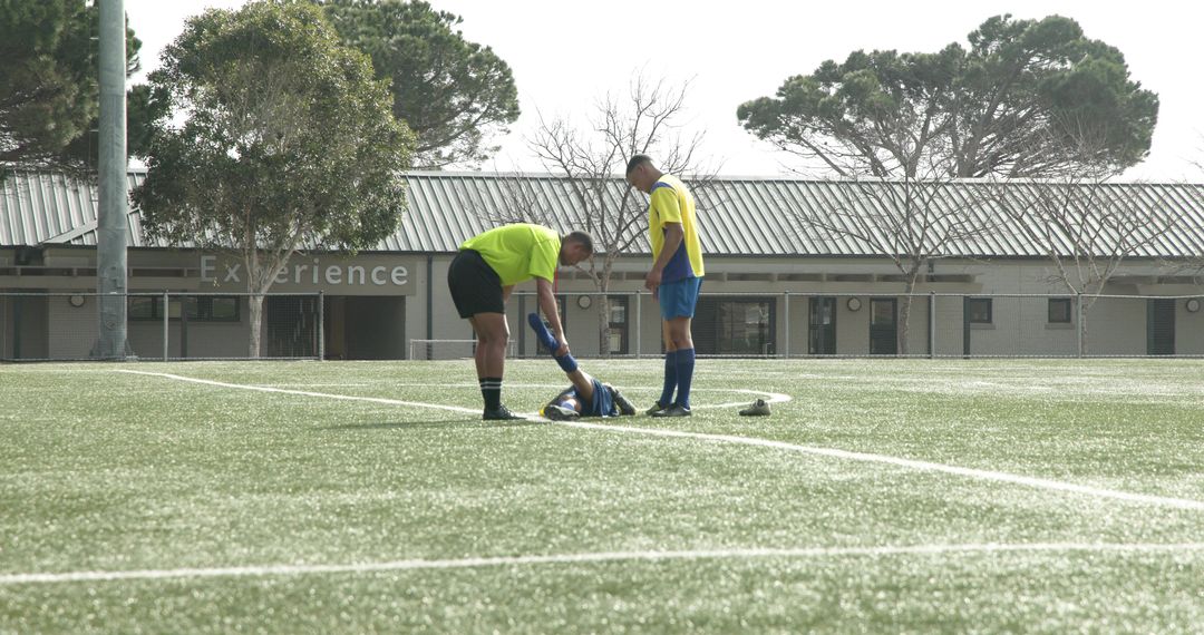 Referee Assisting Injured Soccer Player on Field