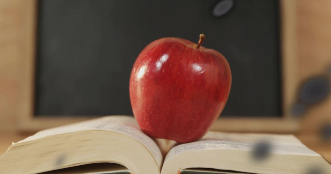 Fresh Red Apple on Open Book in Classroom Setting