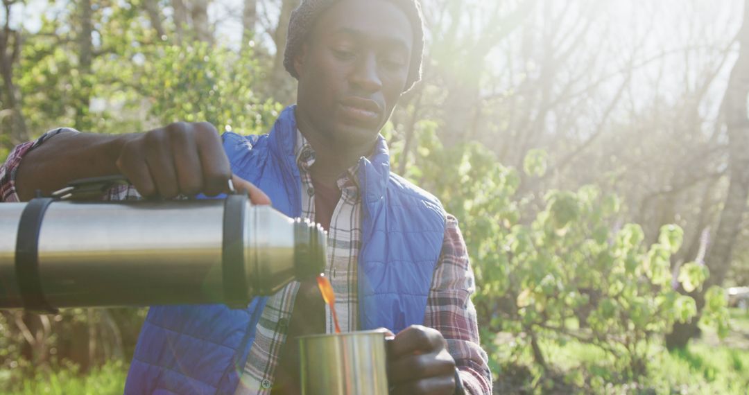 Young Man Pouring Hot Beverage from Thermos in Forest - Free Images, Stock Photos and Pictures on Pikwizard.com