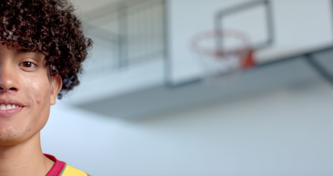 Young Athlete Smiling in Gym Setting with Basketball Hoop