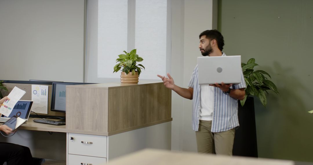 Diverse Team Collaborating with Laptop and Charts in Modern Office Space