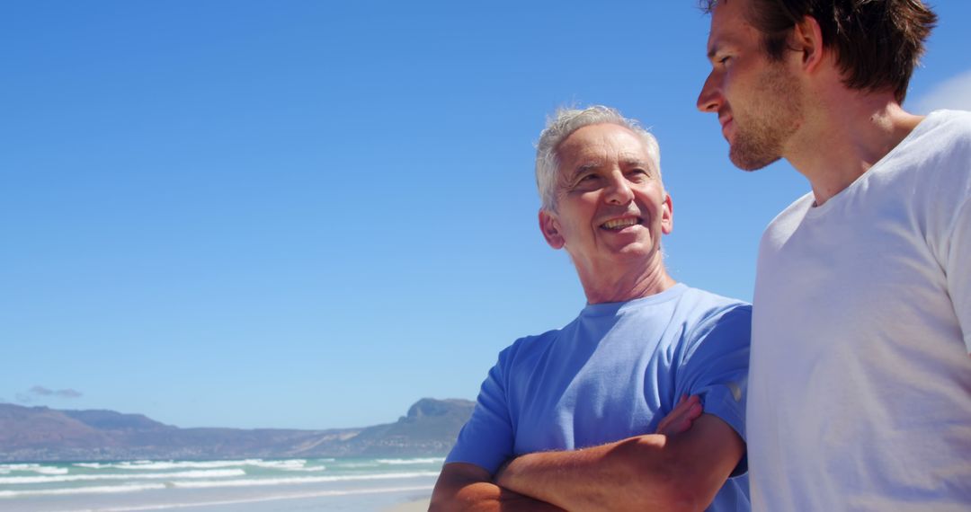 Senior Man with Adult Son Enjoying a Day at Beach Under Blue Sky - Free Images, Stock Photos and Pictures on Pikwizard.com