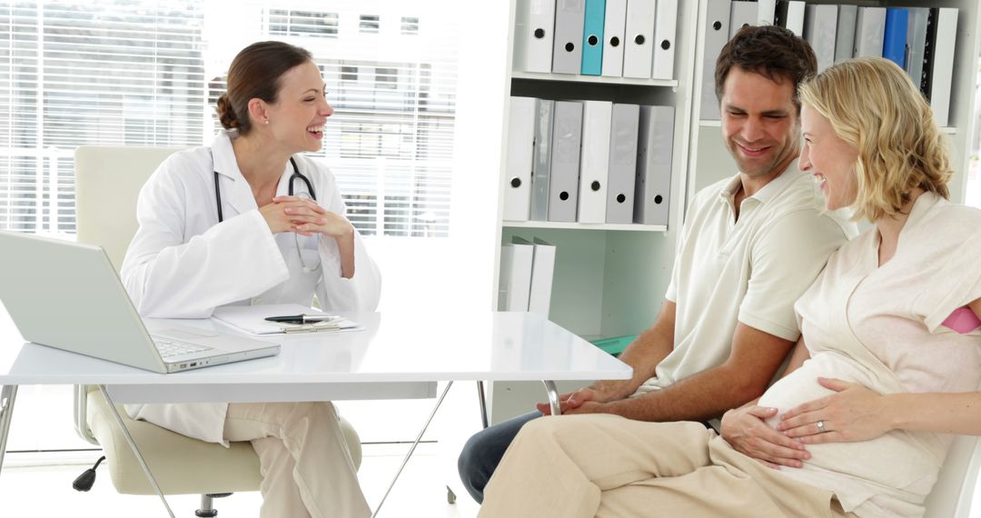 Smiling Doctor Consulting Pregnant Couple in Modern Office - Free Images, Stock Photos and Pictures on Pikwizard.com