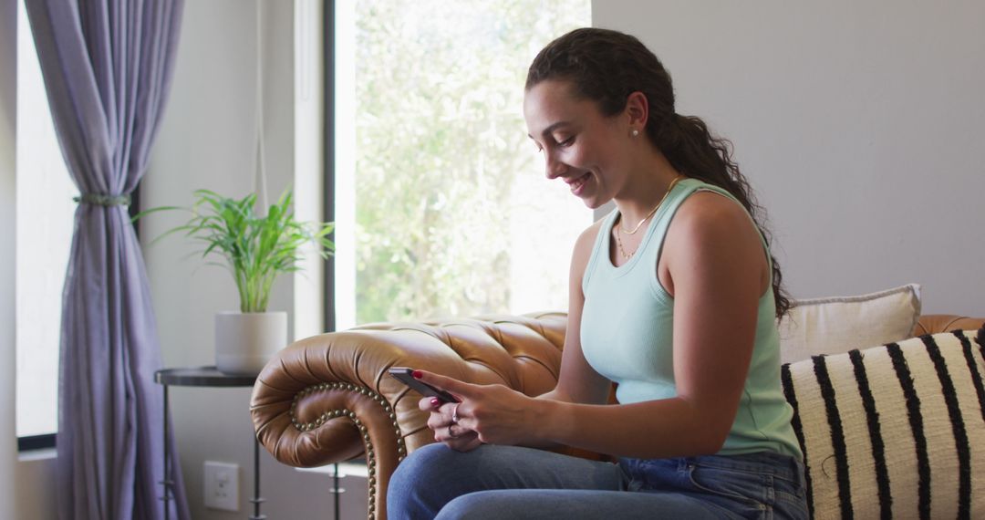Happy Woman Relaxing on Couch with Smartphone at Home