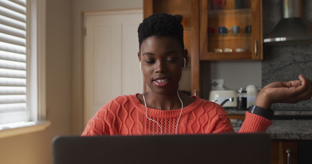 Smiling African American Woman Wearing Earbuds Working on Laptop at Home - Free Images, Stock Photos and Pictures on Pikwizard.com