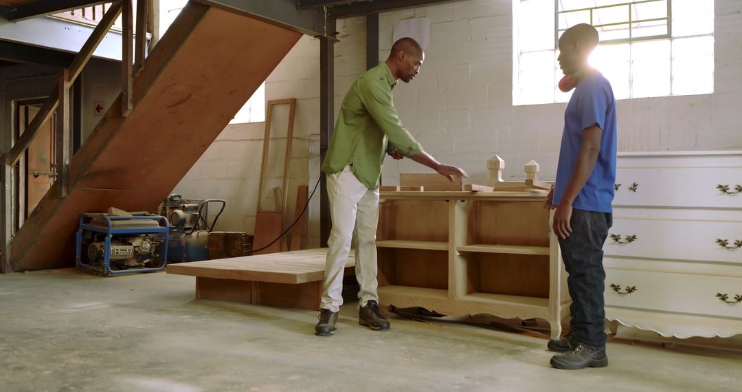 Craftsman Mentoring Apprentice in Woodworking Workshop