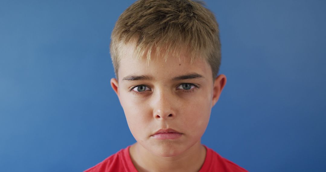 Serious Young Boy Against Blue Background - Free Images, Stock Photos and Pictures on Pikwizard.com