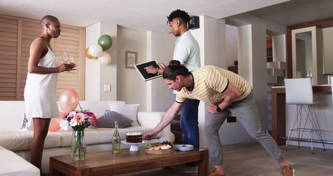 Friends Gather Around Table Arranging Cake and Drinks at Indoor Party
