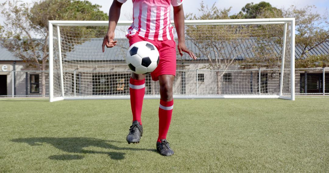 Skillful Soccer Player Juggling Ball on Field Before Goal