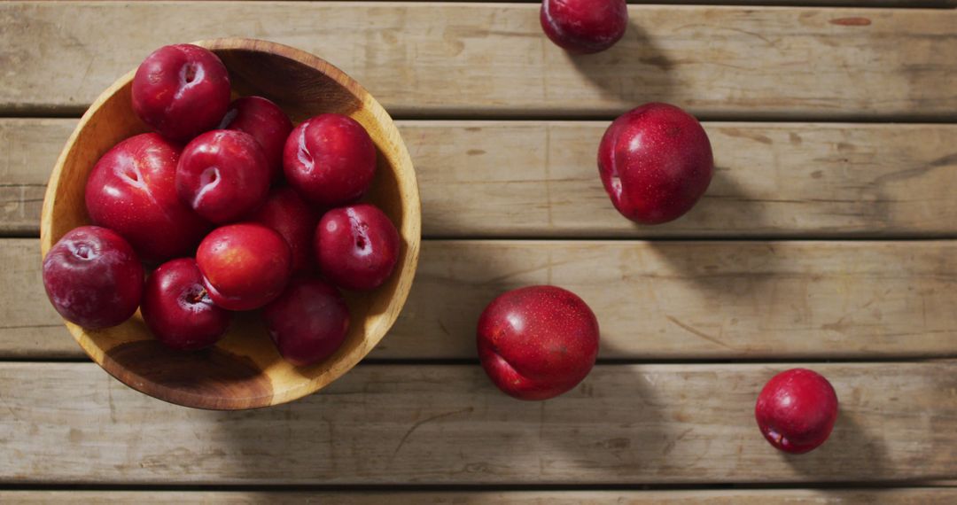 Image of fresh plums in bowl lying on wooden surface - Free Images, Stock Photos and Pictures on Pikwizard.com