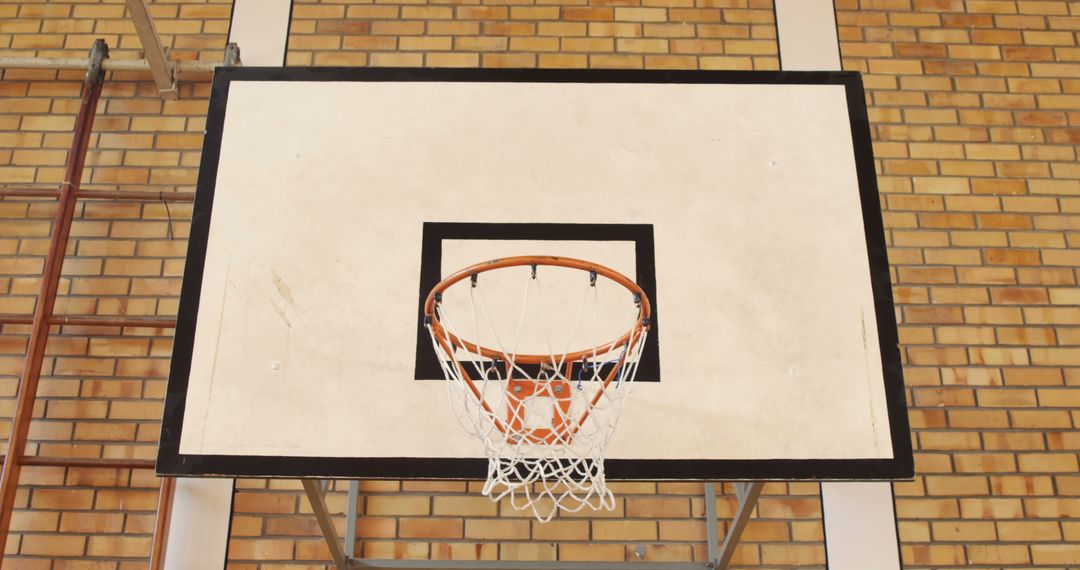 A basketball hoop is mounted against a brick wall backdrop, with copy space - Free Images, Stock Photos and Pictures on Pikwizard.com