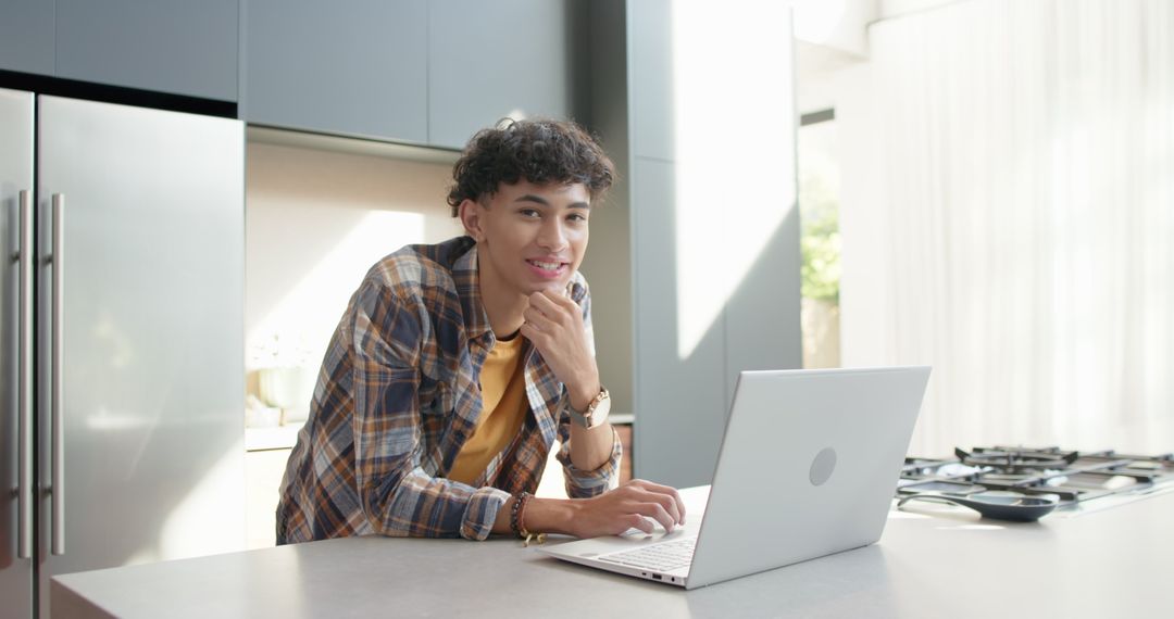 Young Man Working from Home in Modern Kitchen with Laptop