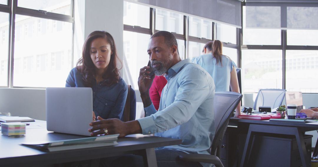 Colleagues Collaborating on Laptop in Modern Office Setting