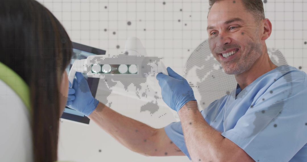 Smiling dentist pointing at dental X-ray on monitor during patient examination in clinic