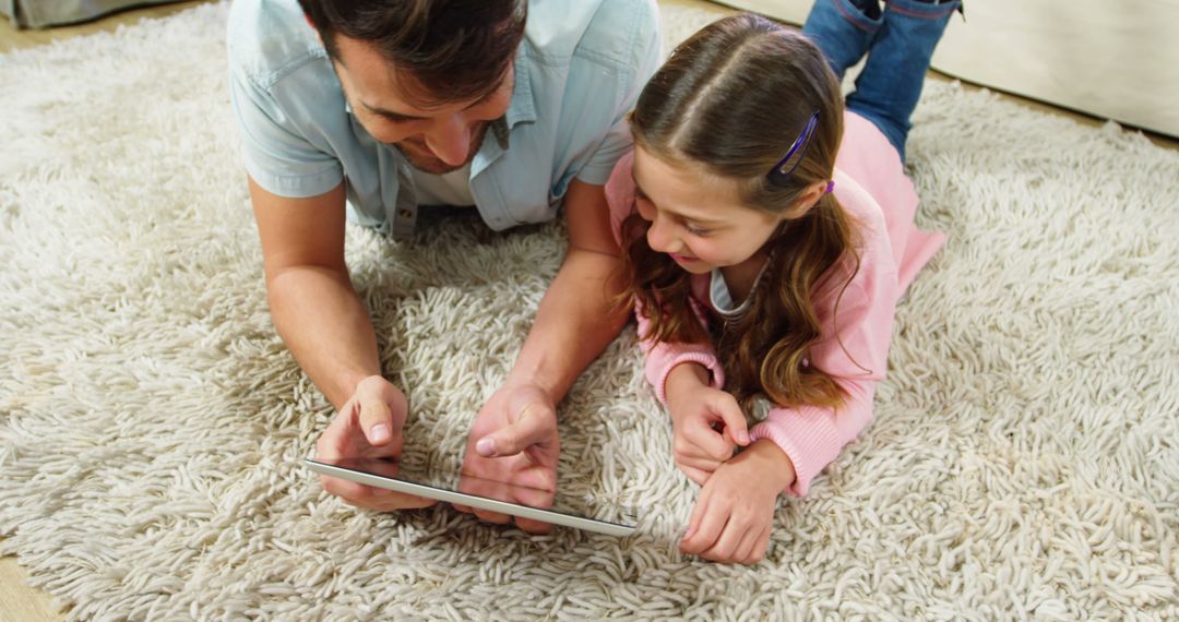 Father and Daughter Using Digital Tablet Together on Cozy Rug - Free Images, Stock Photos and Pictures on Pikwizard.com