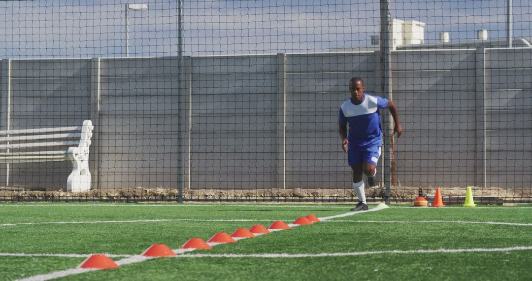 Football Player in Training with Cone Drills on Pitch