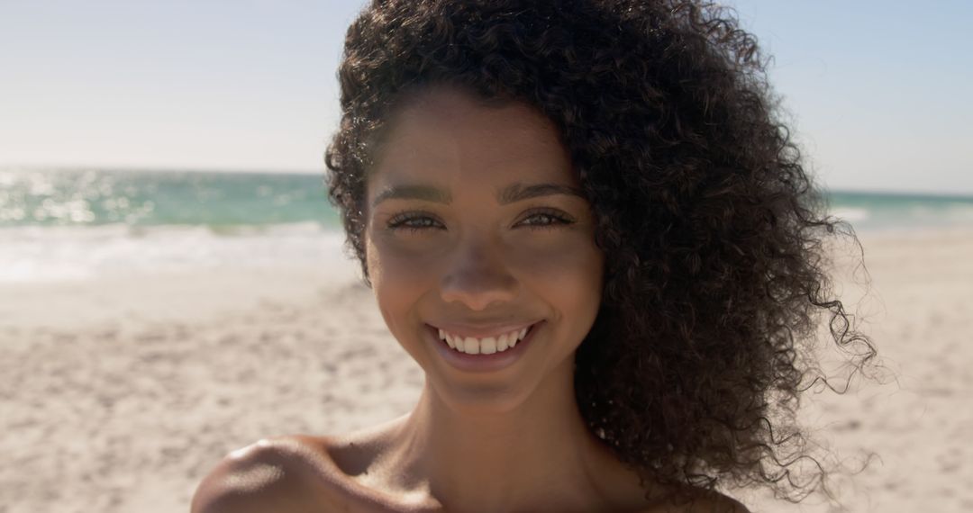 Smiling Young Woman with Curly Hair at Beach on Sunny Day - Free Images, Stock Photos and Pictures on Pikwizard.com