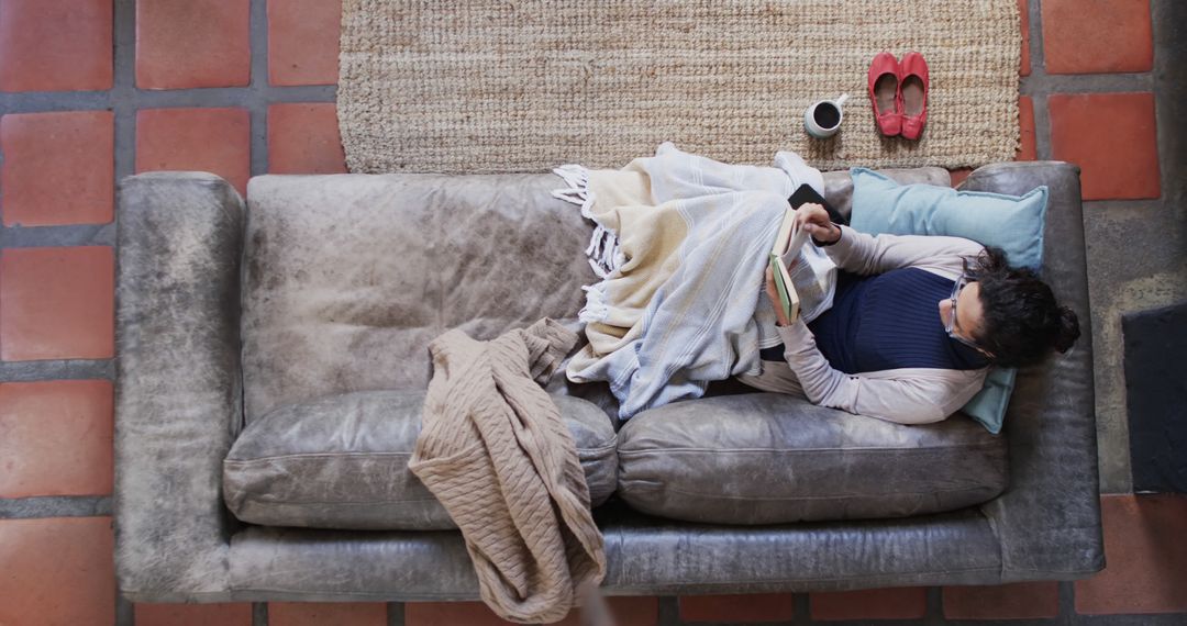 Top View of Woman Relaxing on Couch with Blanket and Book - Free Images, Stock Photos and Pictures on Pikwizard.com