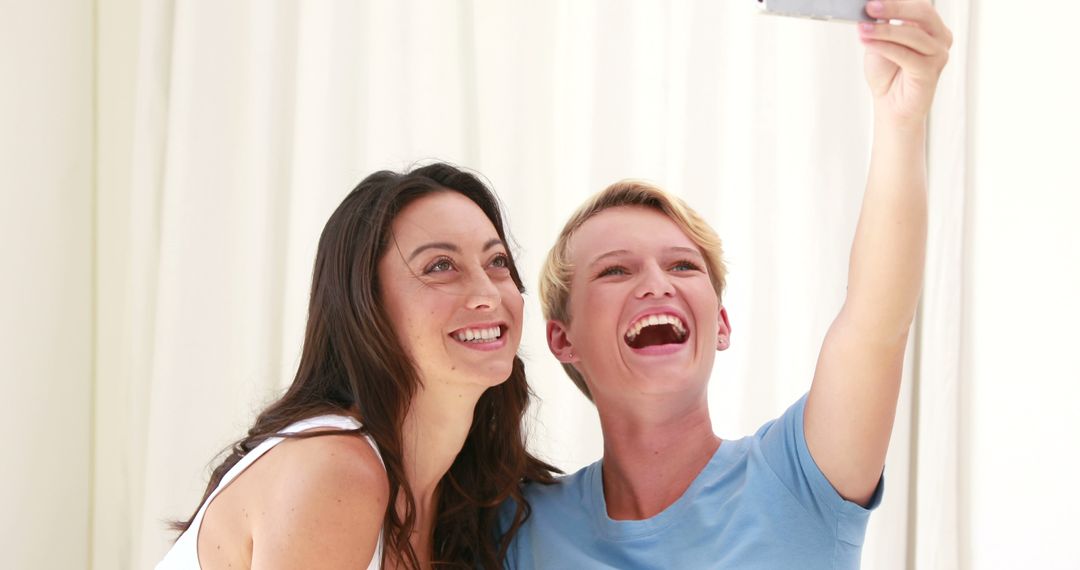 Two friends smiling while taking selfie at home - Free Images, Stock Photos and Pictures on Pikwizard.com