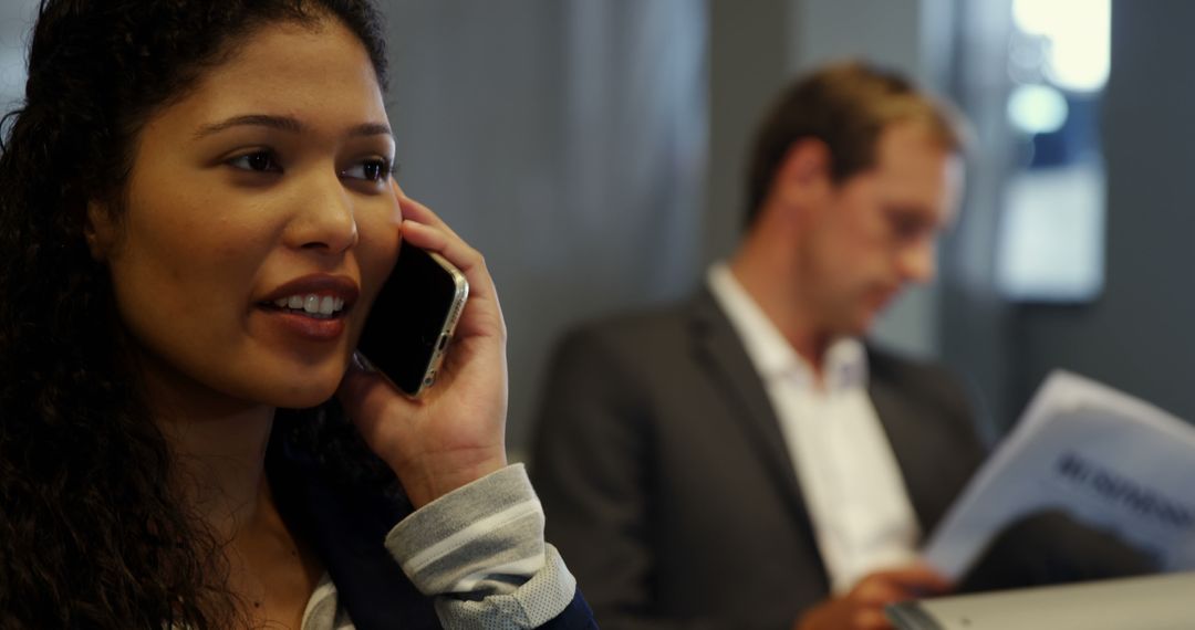 Businesswoman Talking on Phone with Colleague in Background - Free Images, Stock Photos and Pictures on Pikwizard.com