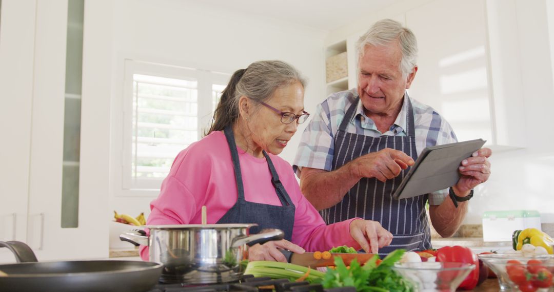 Senior Couple Enjoying Cooking Together While Using Tablet