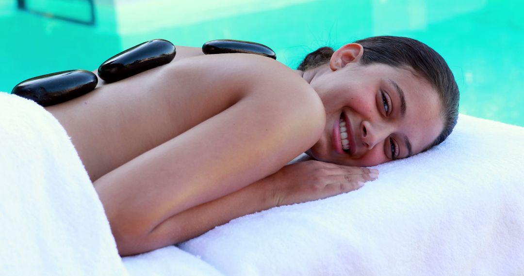 Woman enjoying hot stone massage therapy by swimming pool - Free Images, Stock Photos and Pictures on Pikwizard.com