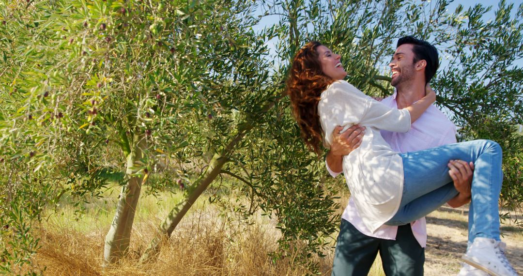 Happy Couple Enjoying Nature and Piggyback Ride in Olive Grove - Free Images, Stock Photos and Pictures on Pikwizard.com