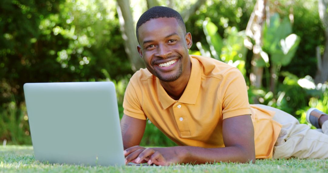 Cheerful Man Lying on Grass Using Laptop in Nature